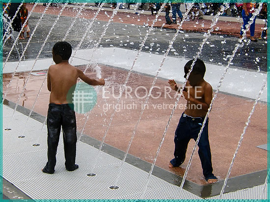 children playing safely with water on a grated pavement